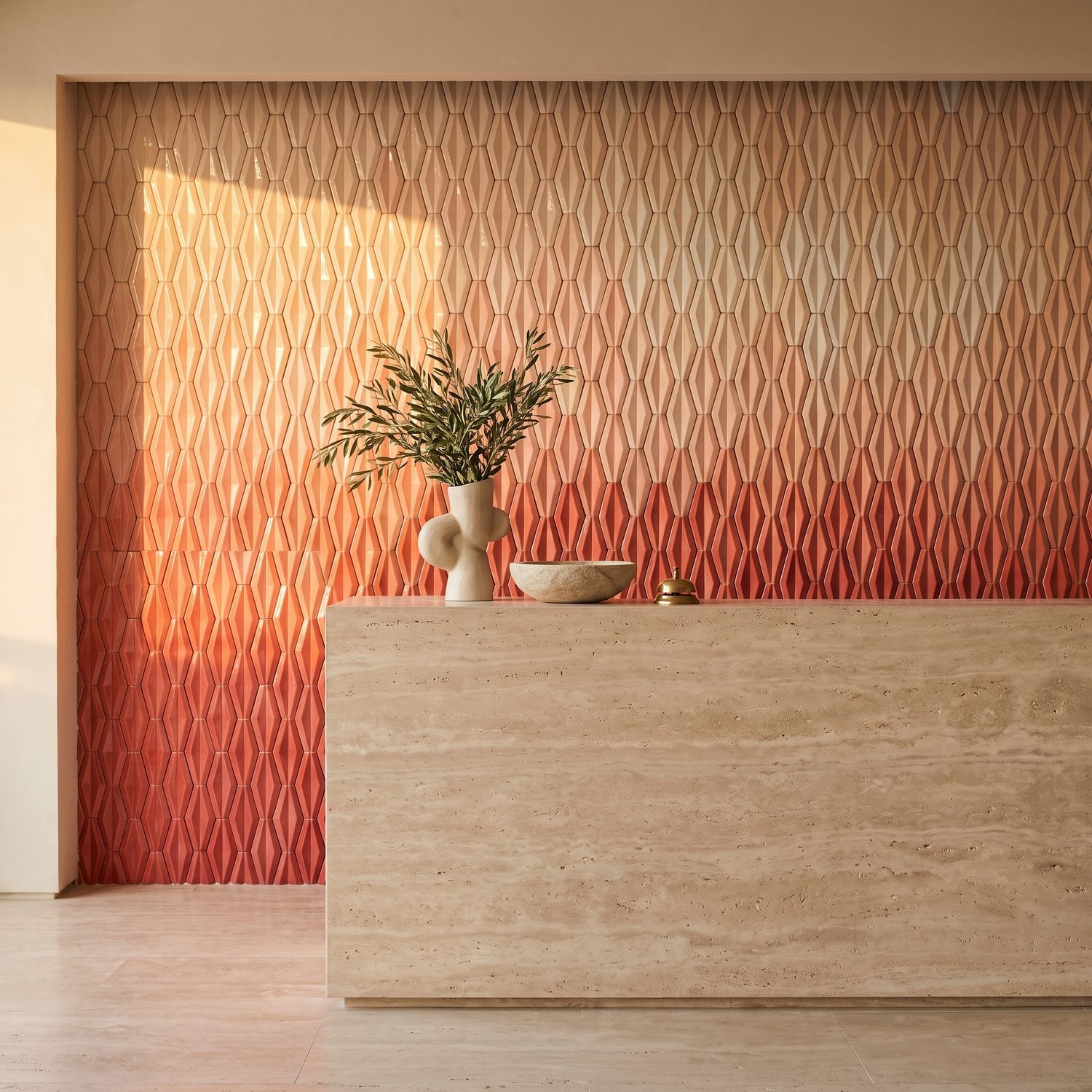 Minimal reception desk in travertine against a patterned coral wall, with a small olive branch arrangement.